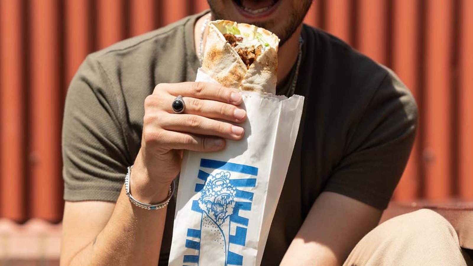 A filled souvlaki in a printed greaseproof-lined bag